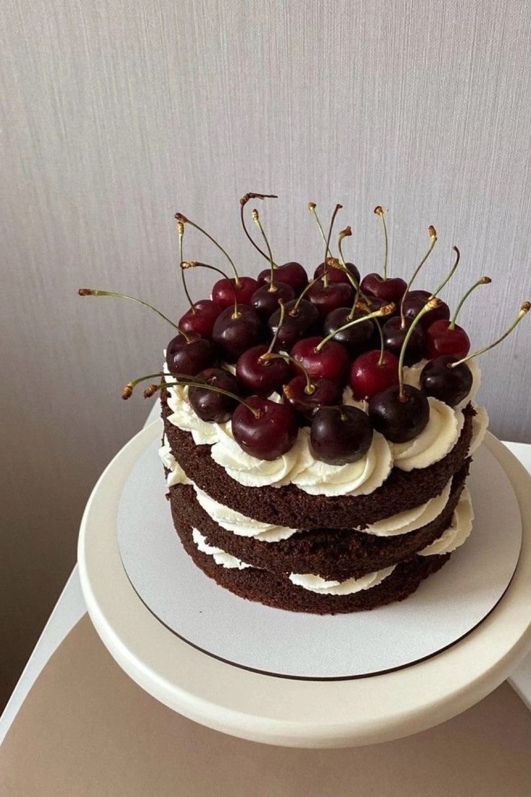 A layered chocolate cake crowned with long-stemmed cherries